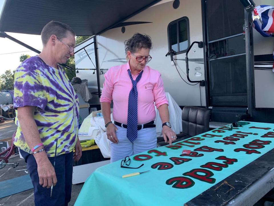 Camp Resolution leaders Sharon Jones, left, and Joyce Williams point towards the banner they have been painting, one of many that decorate the gates of the Camp Resolution site on Colfax Street in Sacramento.