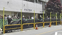 Workers set up a huge black screen on a stretch of sidewalk at Fujikawaguchiko town, Yamanashi prefecture, central Japan Tuesday, May 21, 2024. Just a few weeks ago, the town began setting up a huge black screen to block a view of Mount Fuji because tourists were crowding into the area to take photos with the mountain as a backdrop to a convenience store, a social media phenomenon known as “Mount Fuji Lawson” that has disrupted business, traffic and local life. (Kyodo News via AP)