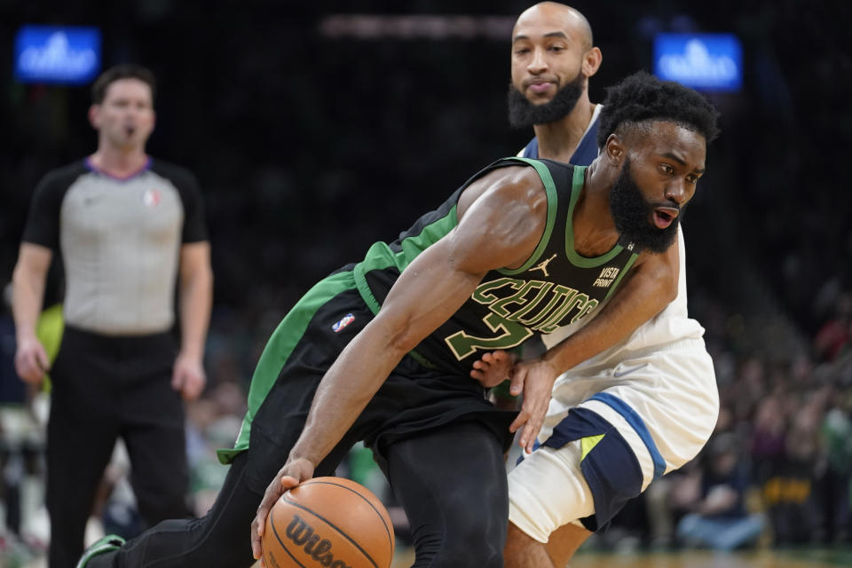 Boston Celtics guard Jaylen Brown (7) drives toward the basket past Minnesota Timberwolves guard Jordan McLaughlin (6) in the first half of an NBA basketball game, Sunday, March 27, 2022, in Boston. (AP Photo/Steven Senne)