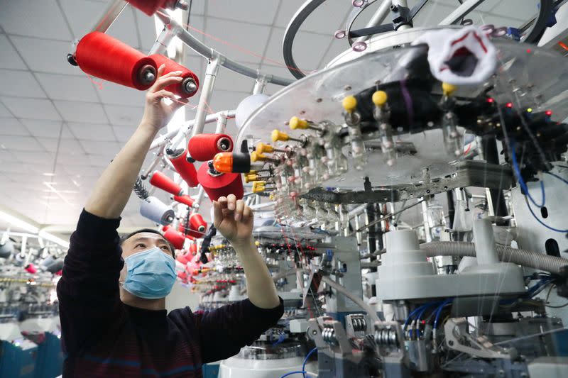 Employee wearing a face mask works on a production line manufacturing socks for export at a factory in Huzhou