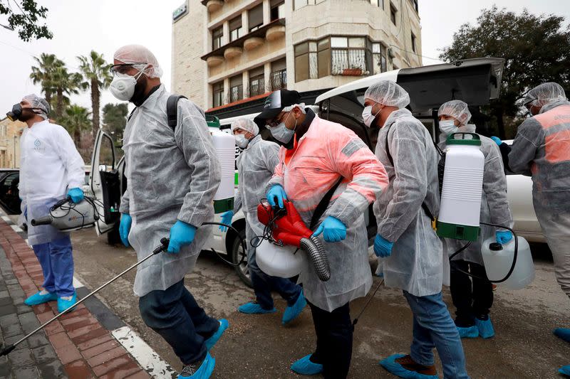 FILE PHOTO: Palestinian workers make their way to disinfect religious sites as preventive measures against the coronavirus, in Ramallah in the in the Israeli-occupied West Bank