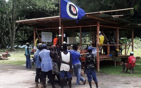 Residents hold a Bougainville flag at a polling station during voting in the non-binding referendum  - Credit: Reuters