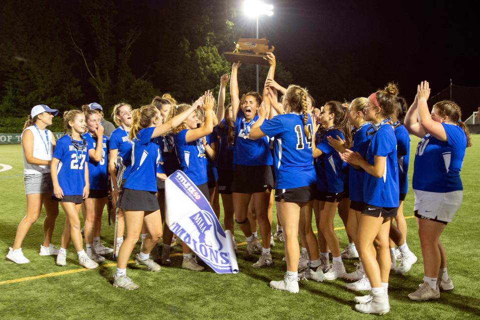 Dover-Sherborn senior captain Rylie Mclaughlin hoists the championship trophy high following the Raiders 10-7 victory over Manchester-Essex in the Division 4 state championship game at Babson College in Wellesley, June 21, 2022.  