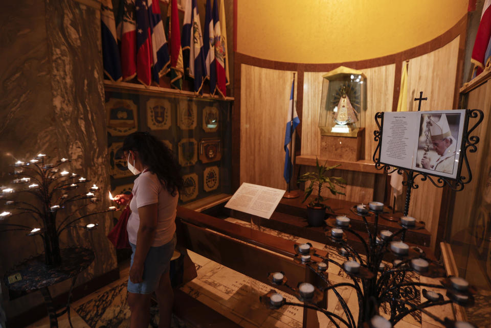 A woman lights a candle past a portrait of Pope Francis in the Argentine church of Santa Maria Addolorata (Our Lady of Sorrows) in Rome, Sunday, July 4, 2021. Pope Francis has been hospitalized for a scheduled surgery for a stenosis, or restriction, of the large intestine, the Vatican said. The news came just three hours after Francis had cheerfully greeted the public in St. Peter's Square and told them he will go to Hungary and Slovakia in September. (AP Photo/Riccardo De Luca)