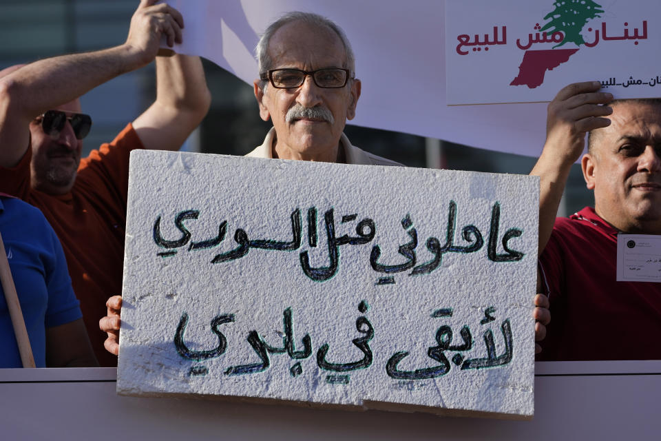 FILE - A Lebanese protester holds an Arabic placard that reads: "Treat me like a Syrian, I can stay in my country," during a protest in front the U.N headquarters against Syrian refugees and the deal between the European Union and the Lebanese government, in Beirut, Thursday, May 9, 2024. Hundreds of Syrians refugees left a remote northeastern Lebanese town back to Syria in a convoy Tuesday, amid a surge in anti-refugee sentiment in the small, crisis-hit country. The new push for repatriation comes as Lebanon's quarrelling ruling political parties have reached a rare consensus in recent years, all agreeing that Syrian refugees should be returned. (AP Photo/Hussein Malla, File)