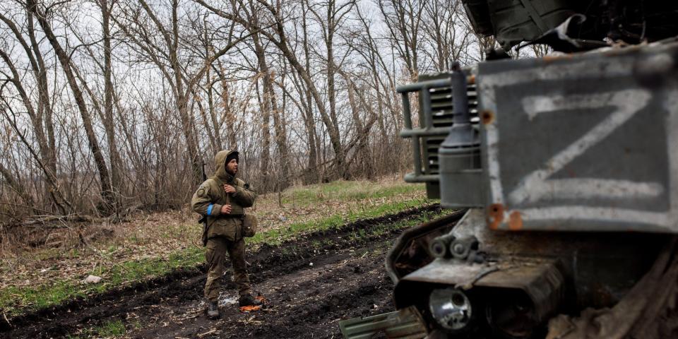 Ukrainian soldier standing next to a destroyed Russian military vehicle in Kharkiv