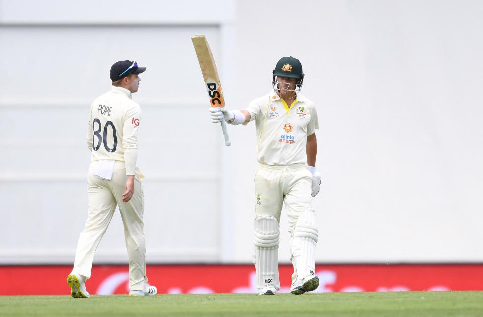 Seen here, David Warner raises his bat after reaching his half-century during day two of the first Ashes Test.