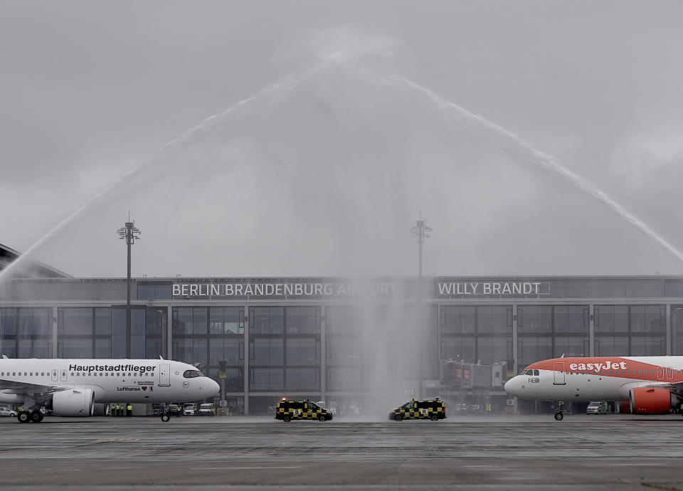 Aircraft belonging to the airlines Lufthansa and easyJet stand after landing under a fountain of water from the airport fire brigade in front of Terminal 1 of the capital airport Berlin Brandenburg "Willy Brandt" (BER). Photo: Michael Kappeler/dpa via Getty Images