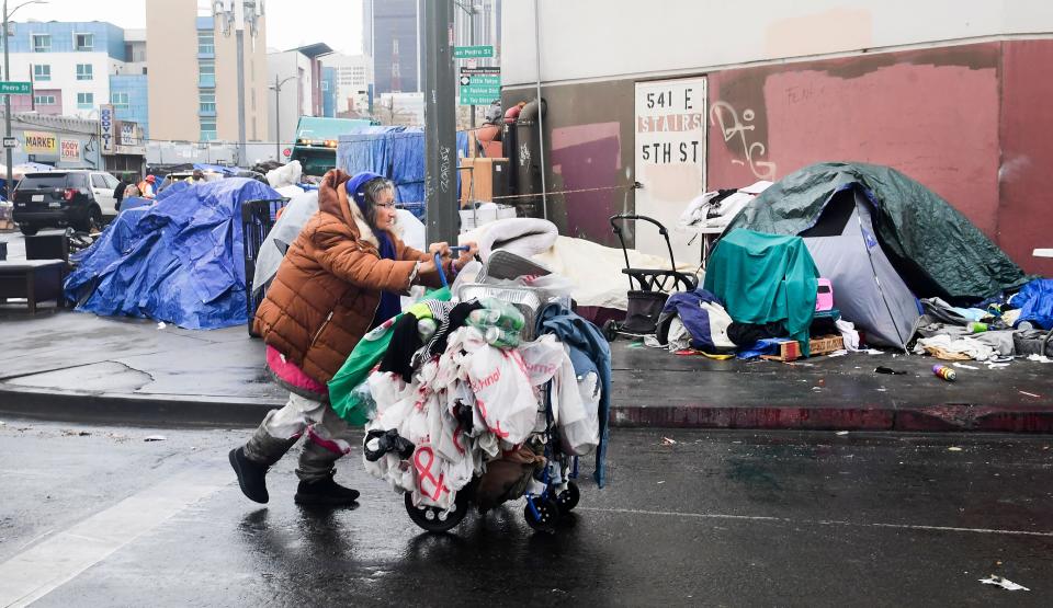 A woman pushes her belongings past a row of tents in Los Angeles on Feb. 1. At last count, more than 4,662 unhoused people were determined to be living in Skid Row. (Photo: FREDERIC J. BROWN via Getty Images)