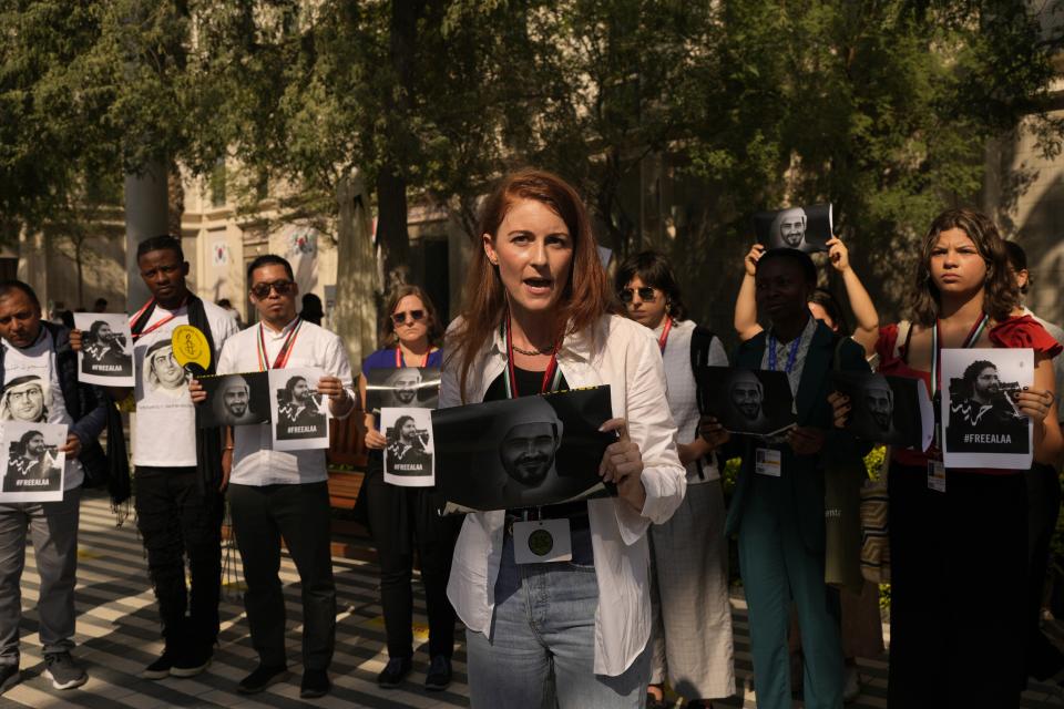 Joey Shea, of Human Rights Watch, speaks during a demonstration with images of jailed activist Mohamed al-Siddiq and Egypt's jailed leading pro-democracy activist Alaa Abdel-Fattah at the COP28 U.N. Climate Summit, Saturday, Dec. 9, 2023, in Dubai, United Arab Emirates. (AP Photo/Rafiq Maqbool)