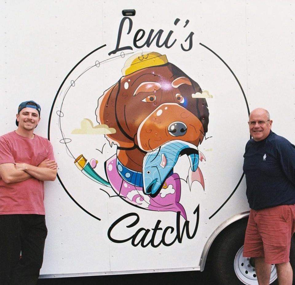 Liam Saunders, left, with his father, right, in front of the Leni's Catch food truck.