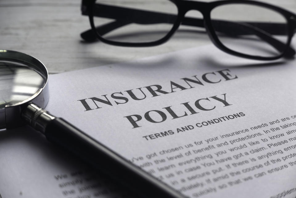 A pair of glasses and magnifying glass on top of Insurance Policy papers. (Source: Getty)