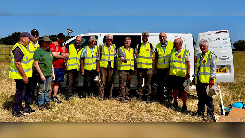 Archaeological group of local volunteers dressed in reflective safety vests.