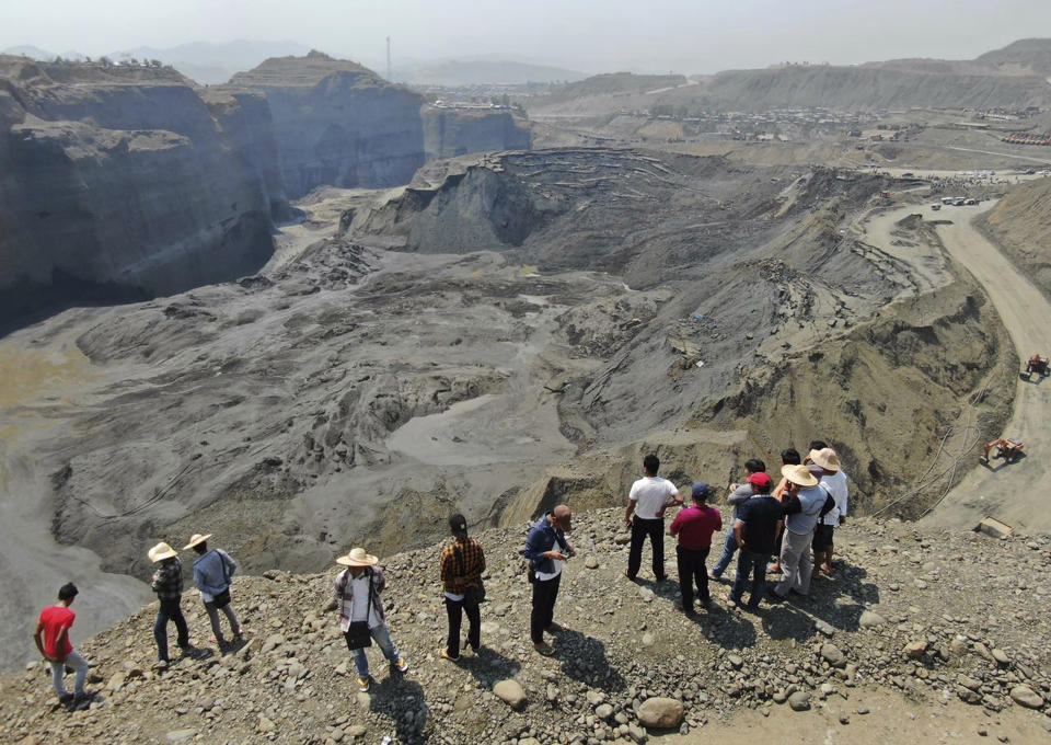 FILE - In this April 23, 2019, file photo, people stand atop a ridge overlooking the scene of a mudslide at a jade gemstone mining site in Hpakant area of Kachin state, northern Myanmar. U.S. sanctions on Myanma Gems Enterprise target an army-controlled gems business rife with corruption and abuses that is one of the junta’s key sources of revenue. State-controlled Myanma Gems is a part of the Ministry of Mines, controls mining and marketing of jade and other gemstones, one of resource-rich Myanmar's most lucrative industries. (AP Photo/Zaw Moe Htet, File)
