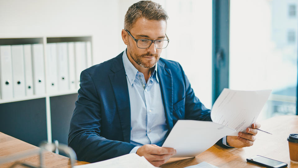 Shot of a mature businessman reading a document at his desk in an office.