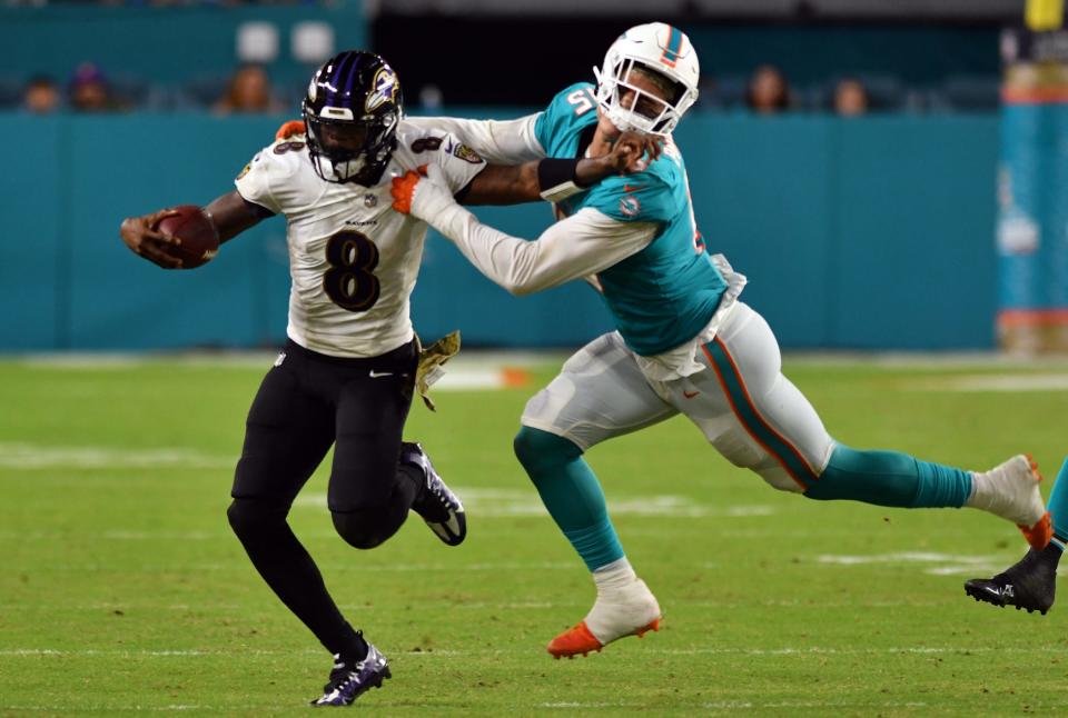 Baltimore Ravens quarterback Lamar Jackson (8) breaks away from Miami Dolphins outside linebacker Jaelan Phillips (15) during the fourth quarter of an NFL game at Hard Rock Stadium in Miami Gardens, Nov. 11, 2021. 