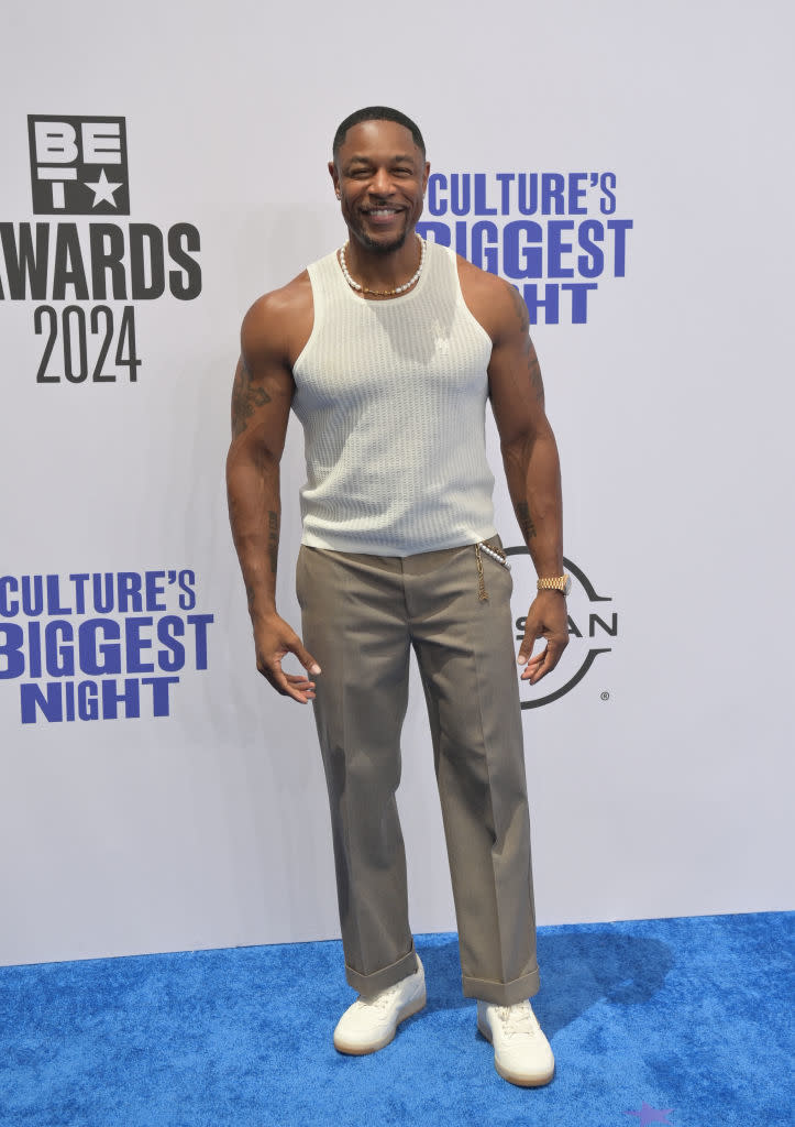 Tank at the BET Awards 2024 red carpet, wearing a sleeveless ribbed white top, beige trousers, and white sneakers