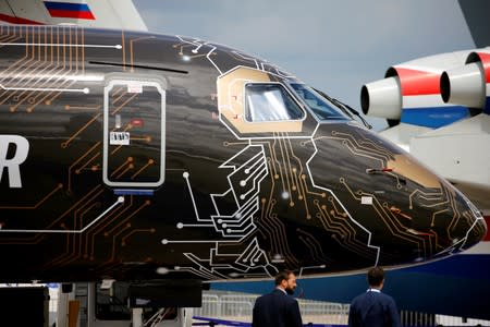 People walk past An Embraer E195-E2 on static display, at the eve of the opening of the 53rd International Paris Air Show at Le Bourget Airport near Paris