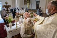 In this photo taken on Sunday, May 24, 2020, Ukrainian Greek Catholic Church priest, Father Vasyl Gasynets distributes Holy Communion during Sunday Mass at a church in Chernivtsi, Ukraine. Gasynets has returned to conducting services at his Greek Catholic church in priestly raiment, but wearing a mask while distributing communion. (AP Photo/Evgeniy Maloletka)