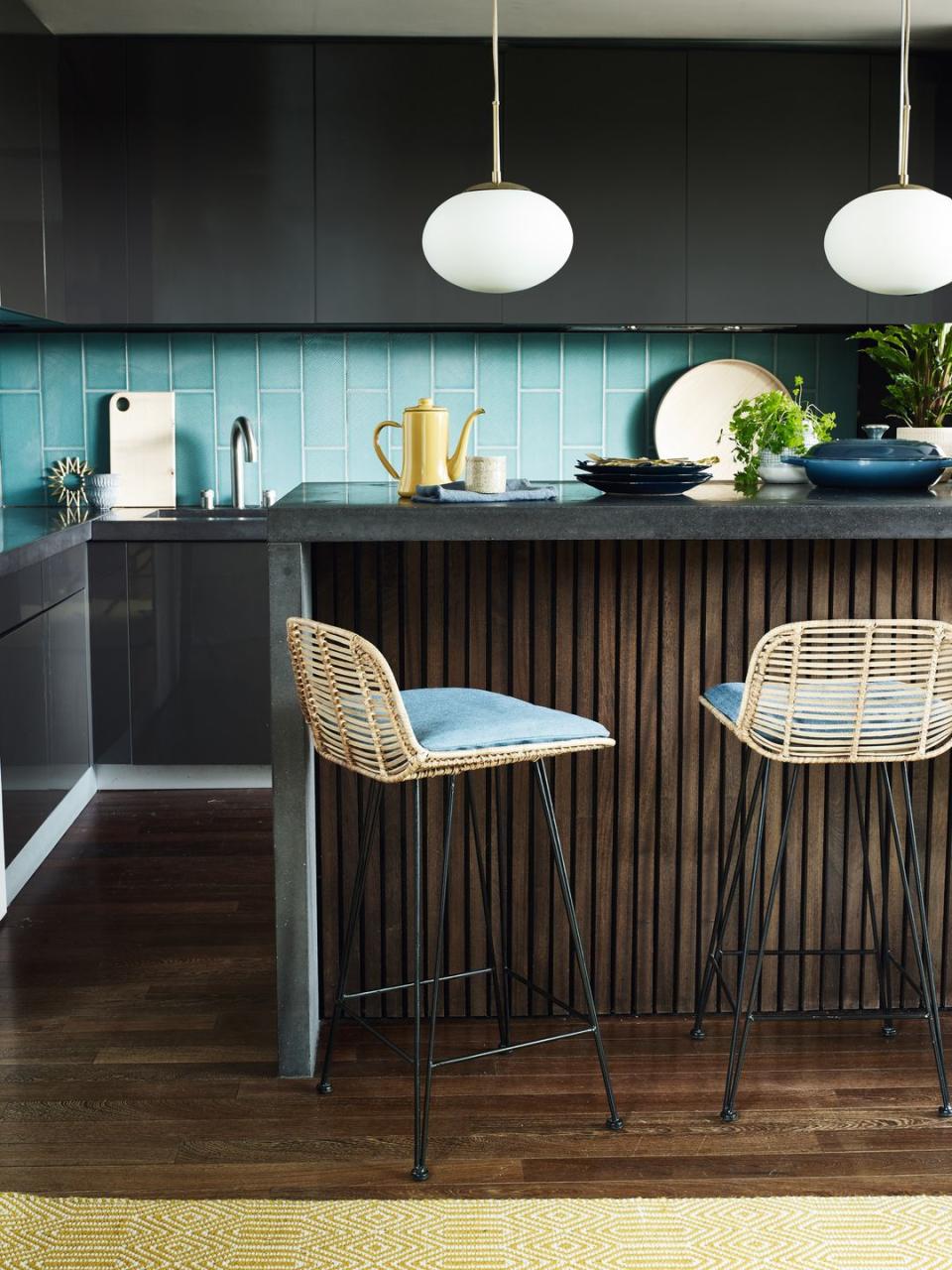 Gray kitchen with dark gray units, breakfast bar and two wicker bar stools