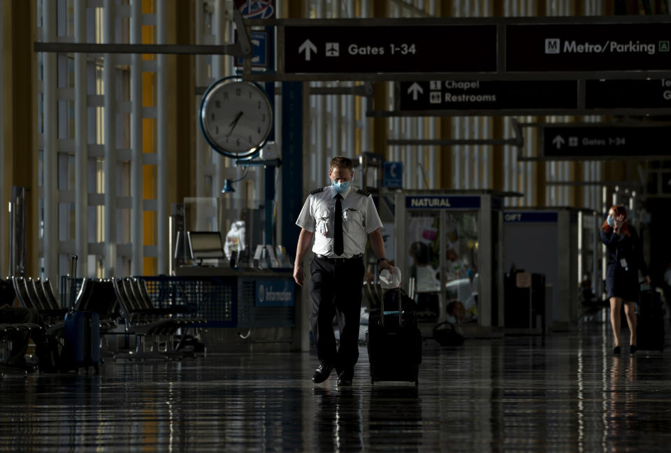 A pilot wearing a protective mask walks through Ronald Reagan National Airport in Arlington (Andrew Harrer / Bloomberg via Getty Images)
