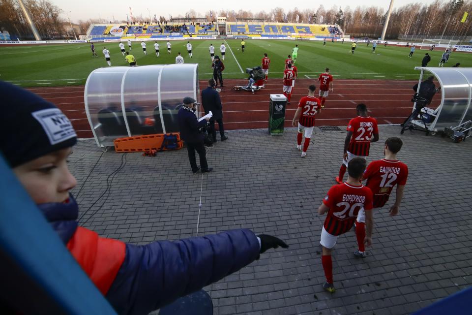 In this photo taken on Friday, March 27, 2020, a boy watches players as they enter the field prior to the Belarus Championship soccer match between Torpedo-BelAZ Zhodino and Belshina Bobruisk in the town of Zhodino, Belarus. Longtime Belarus President Alexander Lukashenko is proudly keeping soccer and hockey arenas open even though most sports around the world have shut down because of the coronavirus pandemic. The new coronavirus causes mild or moderate symptoms for most people, but for some, especially older adults and people with existing health problems, it can cause more severe illness or death. (AP Photo/Sergei Grits)