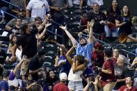 Fans go after a home run hit by Chicago Cubs' Patrick Wisdom during the second inning of a baseball game against the Arizona Diamondbacks, Sunday, May 15, 2022, in Phoenix. (AP Photo/Ross D. Franklin)