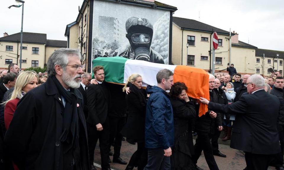 Sinn Féin president Gerry Adams (left) watches on as mourners carry Martin McGuinness’s coffin past the murals at Free Derry Corner.