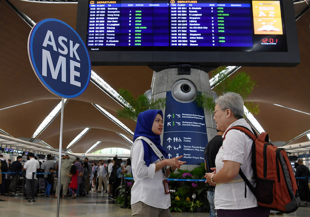 A MAHB Airport CARE Ambassador assists a passenger at KLIA in Sepang August 22, 2019, during a systems outage. — Bernama pic