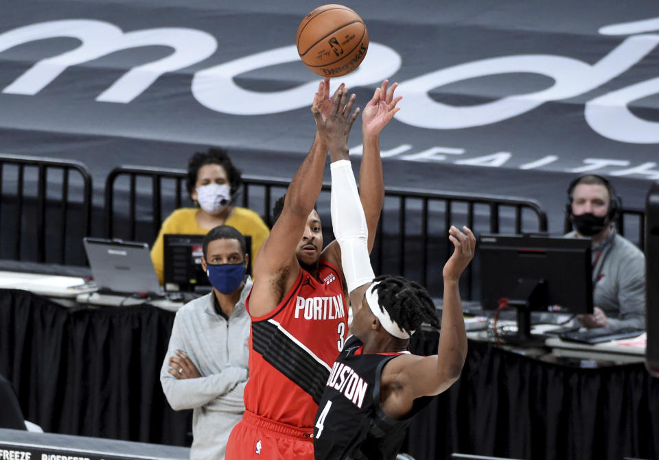 Portland Trail Blazers guard CJ McCollum, left, hits a shot over Houston Rockets forward Danuel House Jr. to give the Blazers the lead late in overtime of an NBA basketball game in Portland, Ore., Saturday, Dec. 26, 2020. The Blazers won 128-126 (AP Photo/Steve Dykes)