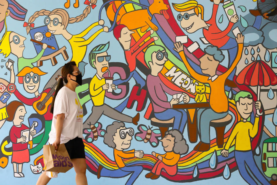 A woman wearing a protective mask walks past a wall mural on 31 May, 2020, in Singapore. (PHOTO: Getty Images file photo)