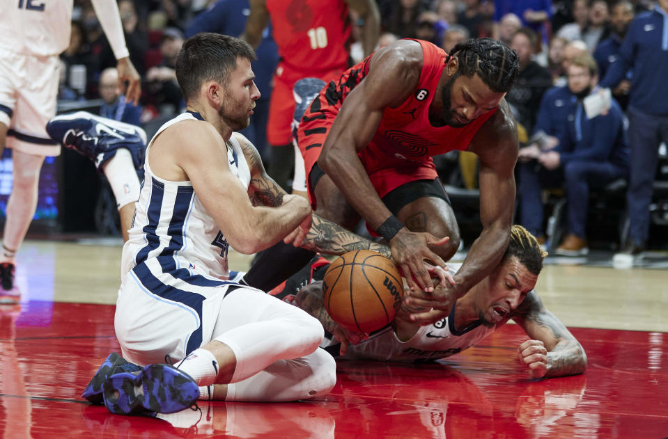 Portland Trail Blazers forward Justise Winslow, center, and Memphis Grizzlies guard John Konchar, left, and forward Brandon Clarke dive for a loose ball during the second half of an NBA basketball game in Portland, Ore., Wednesday, Nov. 2, 2022. (AP Photo/Craig Mitchelldyer)