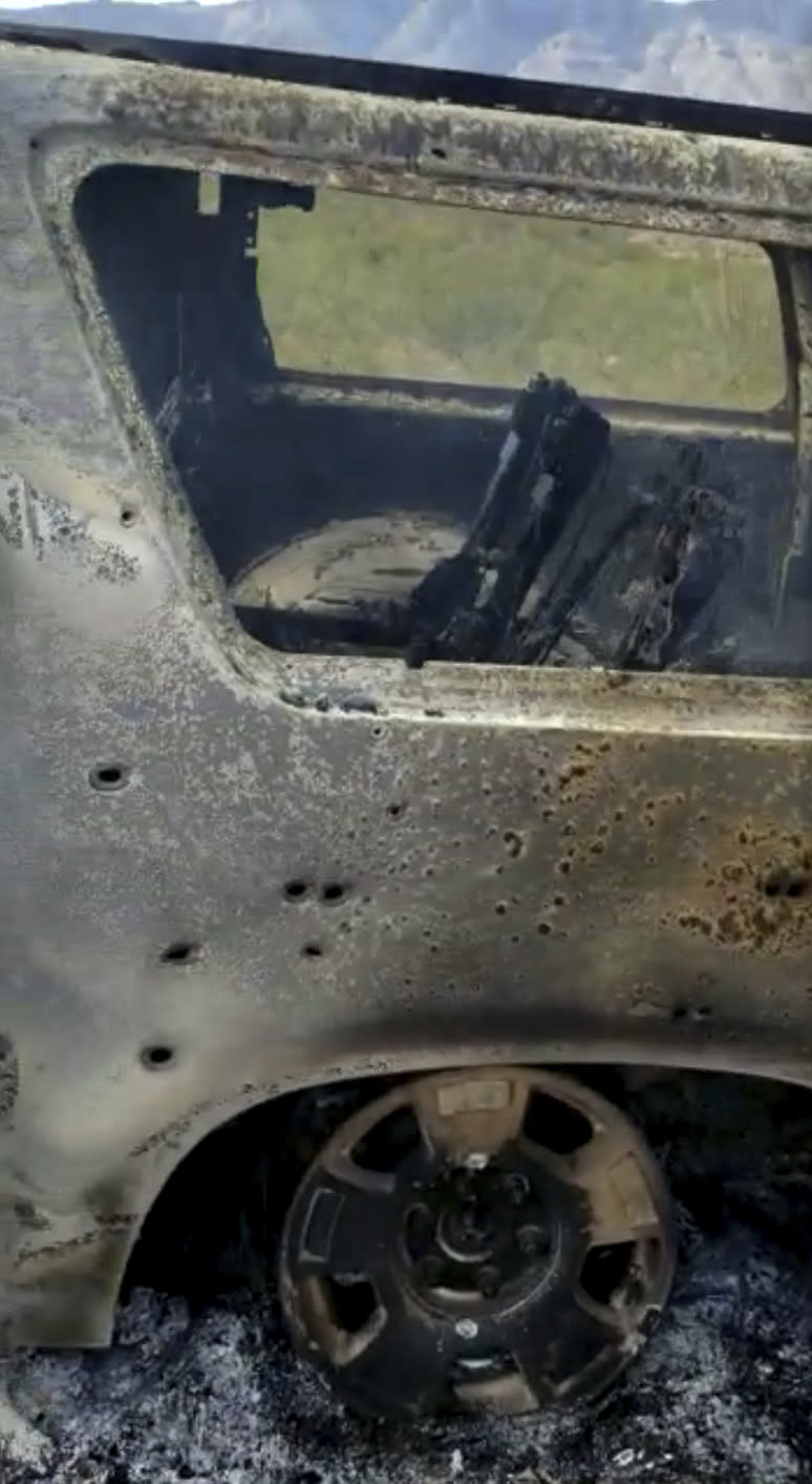 This frame from Nov. 4, 2019, video by Kenny Miller and posted on the Twitter account of Alex LeBaron shows a burned-out vehicle that was being used by some members of the LeBaron family as they were driving in a convoy near the Sonora-Chihuahua state border in Mexico. Mexican authorities say drug cartel gunmen ambushed multiple vehicles, including this one, slaughtering several women and children. (Kenny Miller/Courtesy of Alex LeBaron via AP)