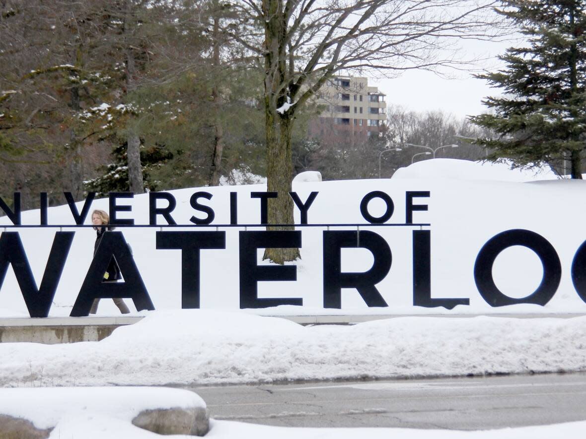 A person walks by the University of Waterloo sign on campus in Februrary 2020. The school is pulling 29 vending machines from campus that were found to have a form of facial recognition technology.  (Kate Bueckert/CBC - image credit)