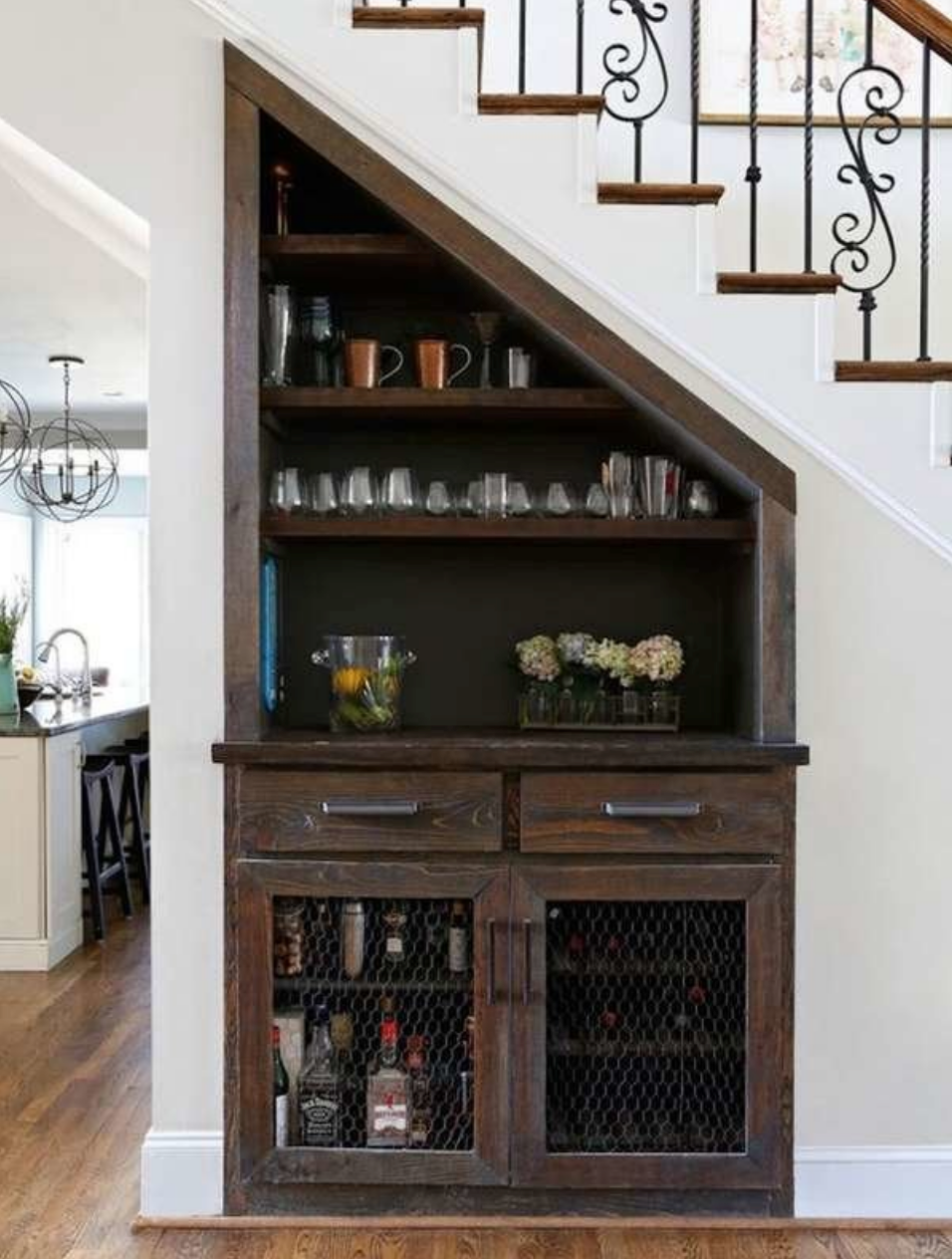 view of dark wood cabinet and mini bar underneath elegant staircase in open plan living room