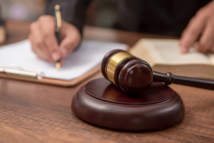 Person signs documents near a gavel, symbolizing legal activity or judiciary concept