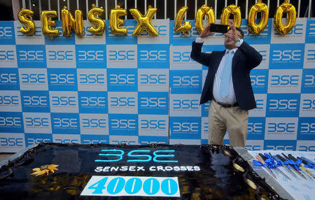 A man uses his mobile phone to take pictures next to a cake to celebrate the Sensex index rising to over 40,000, in Mumbai, India, May 23, 2019. REUTERS/ Francis Mascarenhas