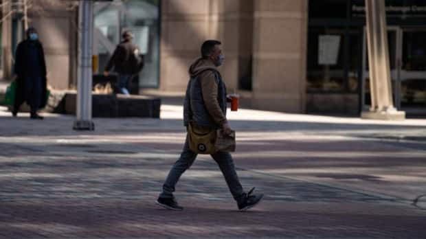 A pedestrian in a mask crosses the street in downtown Ottawa in early April 2021.