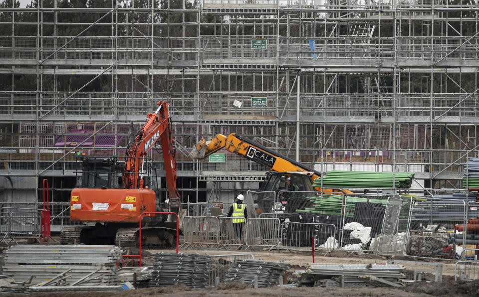 Work continues on a home building site in the day after Prime Minister Boris Johnson put the UK in lockdown to help curb the spread of the coronavirus, Larbert, central Scotland, Tuesday March 24, 2020.  Essential workers including the construction industry are allowed to continue working with guidance about social distancing. For some people the COVID-19 coronavirus causes mild or moderate symptoms, but for others it causes severe illness. (Andrew Milligan / PA via AP)