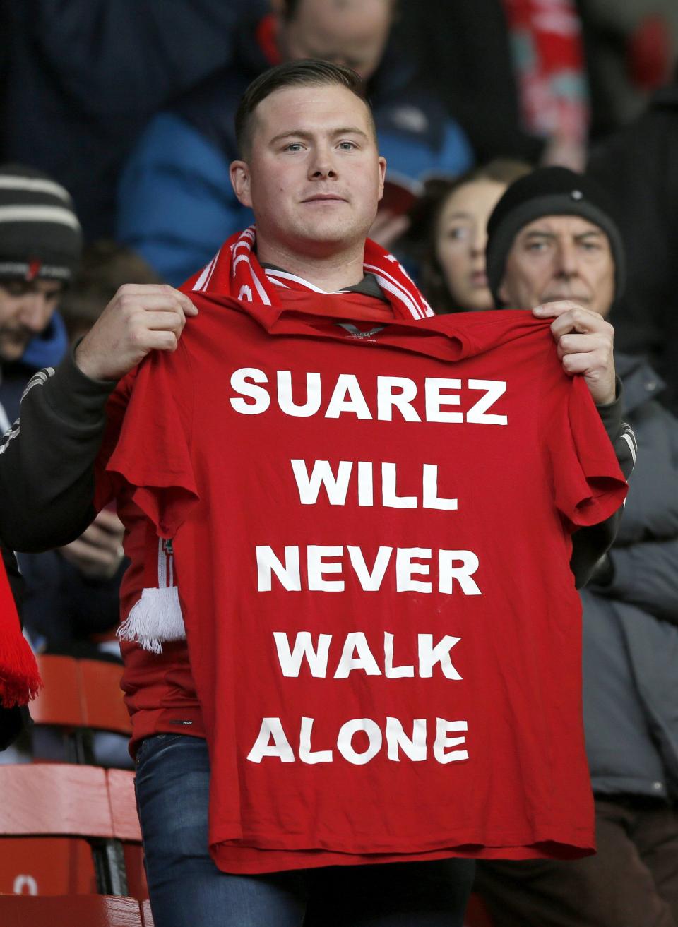 A Liverpool fan holds up a football shirt before their English Premier League soccer match against Fulham at Anfield in Liverpool, northern England November 9, 2013.