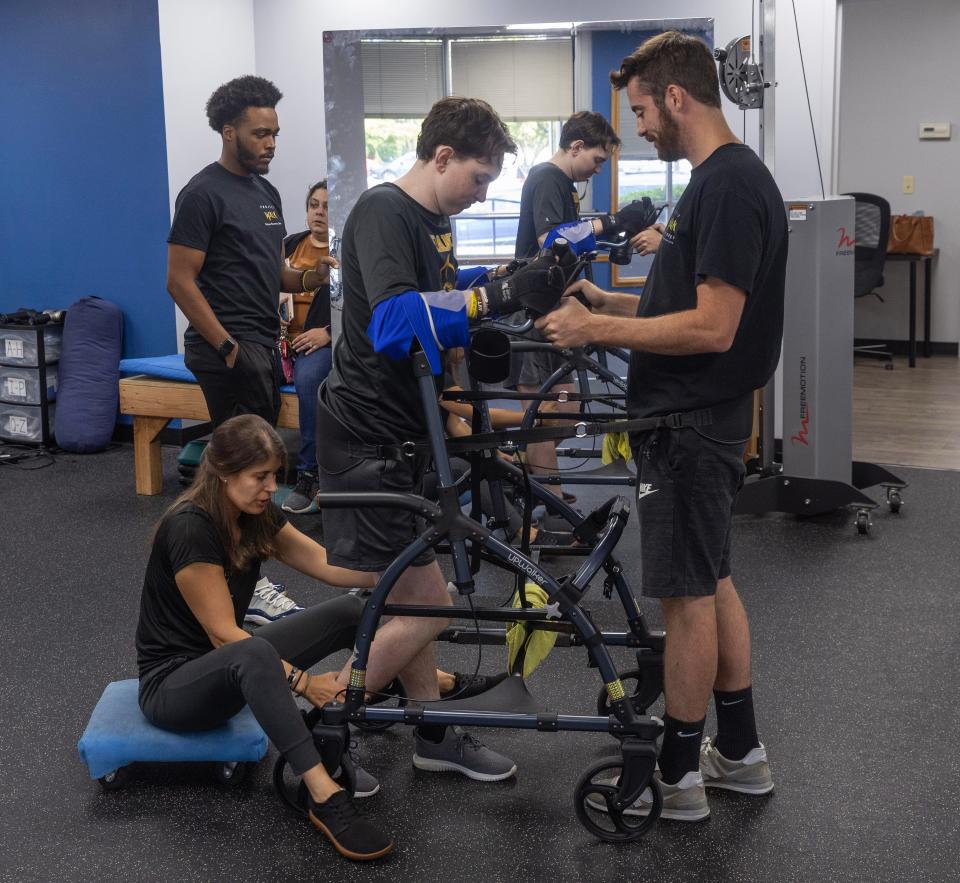 Matt Fumo and Daniella Rivka help Aaron Van Trease as he works with the wheeled walker, slowly going around the facility at Project Walk in Mount Laurel.