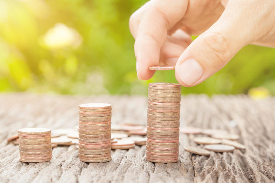 A hand places a coin on top of the largest stack, in a series of progressively taller stacks.