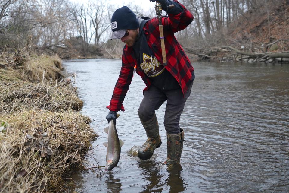 Pat Kiehm of Milwaukee lands a steelhead, or rainbow trout, while fishing on the Menomonee River in Wauwatosa.