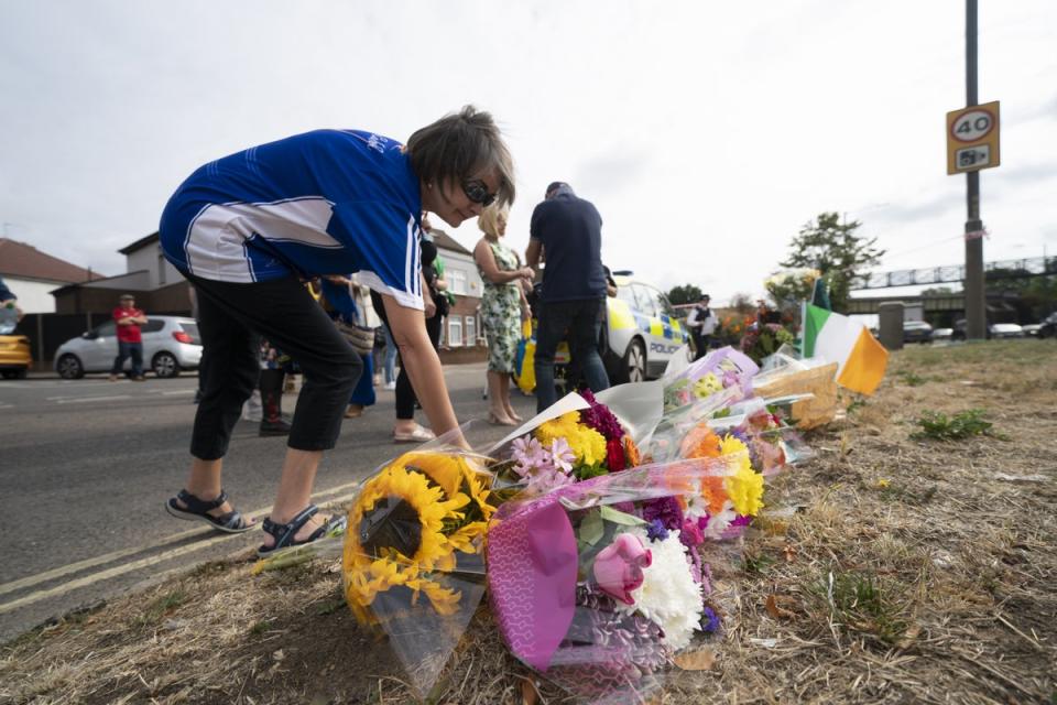A woman lays flowers on Western Avenue Frontage Road in Greenford (Kirsty O’Connor/PA) (PA Wire)