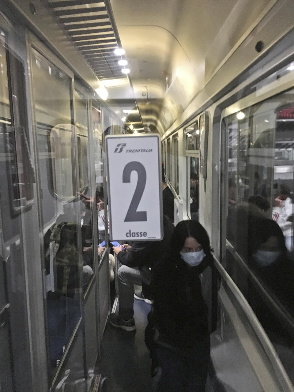 A woman wears a mask as people crowd a train from Padua, northern Italy, to Rome, early Sunday, March 8, 2020. Chaos and panic reigned as rumors spread that the Italian government was expanding its lockdown on Northern Italy to help contain the coronavirus, and many people tried to leave before being locked in one of the red areas. (AP Photo/Patricia Thomas)