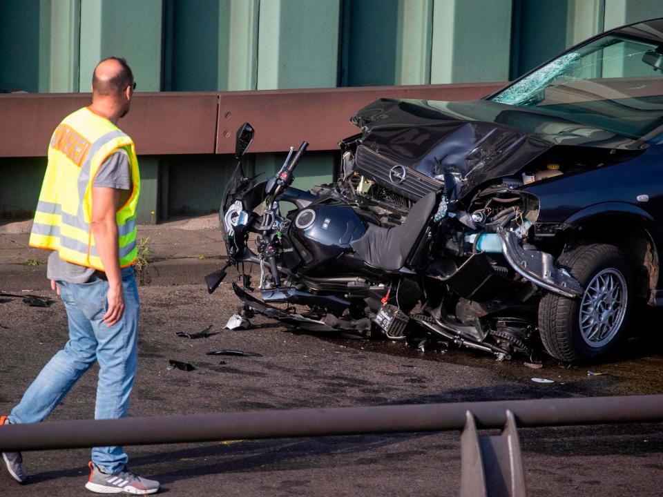 Police officer walks past battered motorcycle and car after a series of crashes on the Berlin motorway: AFP via Getty Images