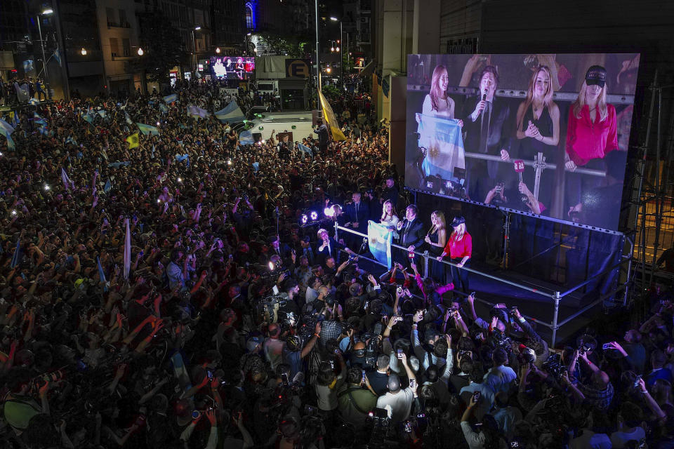 Presidential candidate of the Liberty Advances coalition Javier Milei speaks to supporters outside his campaign headquarters after winning the runoff election in Buenos Aires, Argentina, Sunday, Nov. 19, 2023. At left is his running mate Victoria Villarruel, second from right his girlfriend Fatima Florez and at right his sister Karina Milei. (AP Photo/Matias Delacroix)