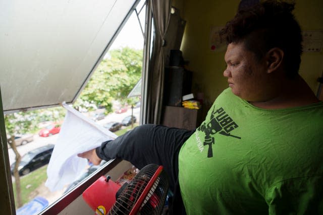 Mohamad Nor Abdullah adjusts a white flag outside the window of his rented room in Kuala Lumpur, Malaysia (Vincent Thian/AP)