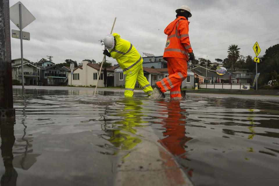 Santa Cruz County public works employees clear a storm drain in the Rio Del Mar neighborhood of Aptos, Calif., Wednesday, Dec. 20, 2023 (AP Photo/Nic Coury)