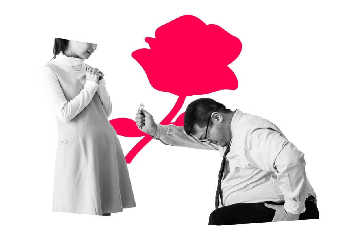 A man on one knee holds out an engagement ring to a woman clasping her hands. Behind them is an illustrated rose.